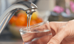 Person filling glass with water from tap