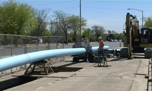 Construction worker next to large water pipe