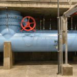 A large blue pipe labeled settled water runs horizontally with a red wheel placed in front to adjust the water flow.
