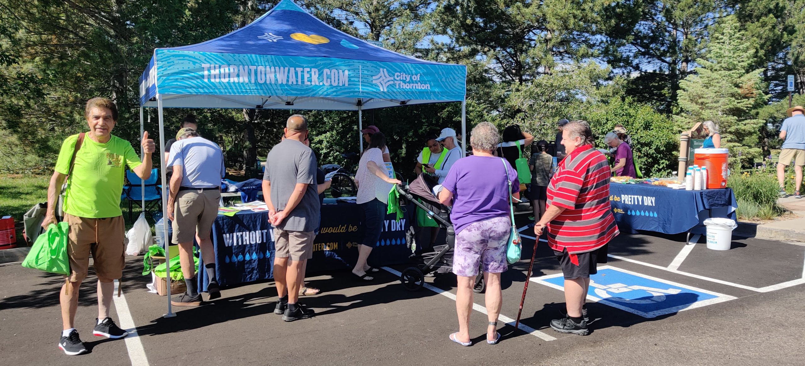 Blue tent that reads "without water, life would be pretty dry" in a parking lot and multiple people surrounding the tent.