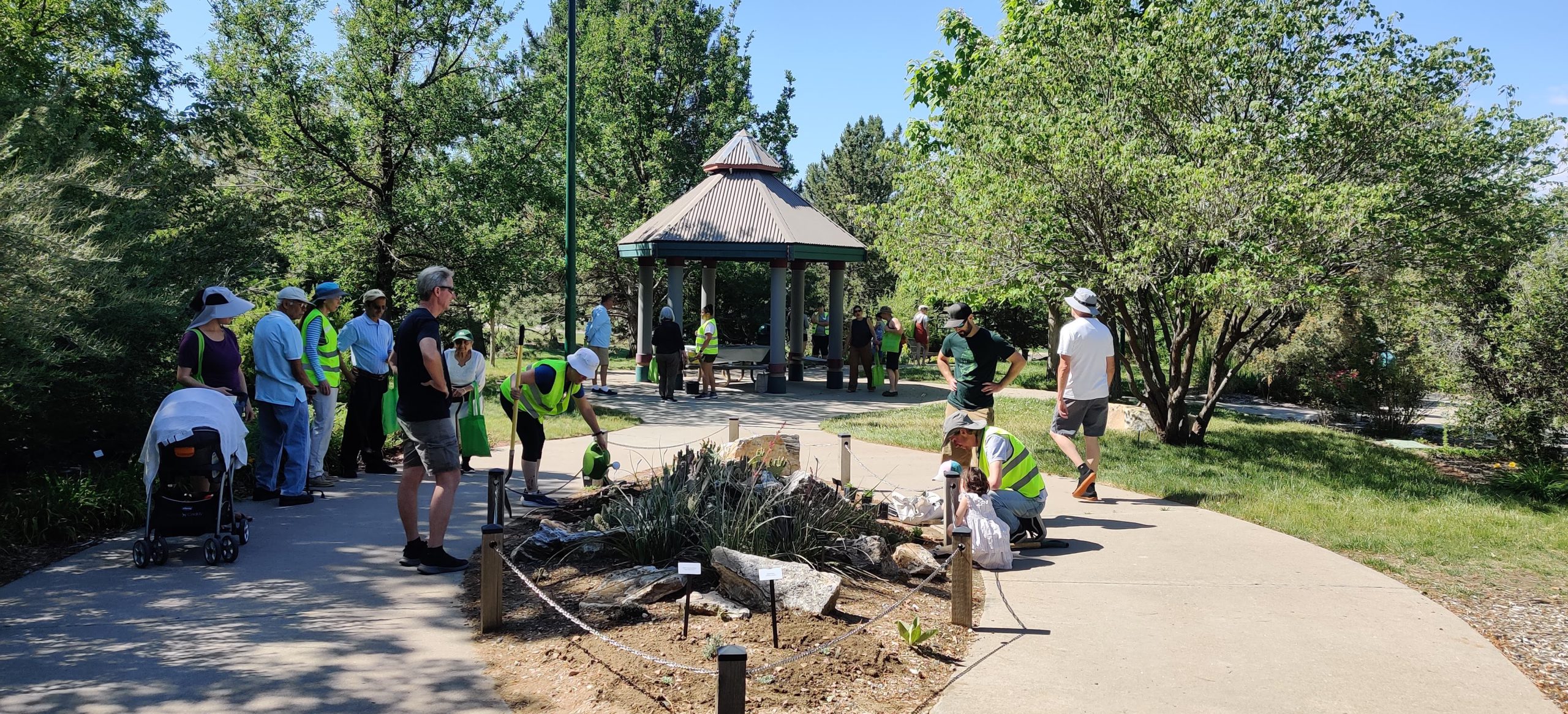 A garden pathway leads to a gazebo. Multiple event attendees stand on the pathway.