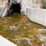 River water flowing over rocks out of a mountain tunnel.