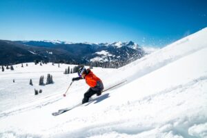 Person in red coat and dark pants turns while skiing.