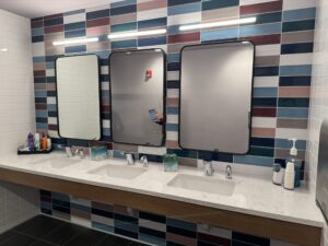 Three mirrors mounted on a tile wall above sinks